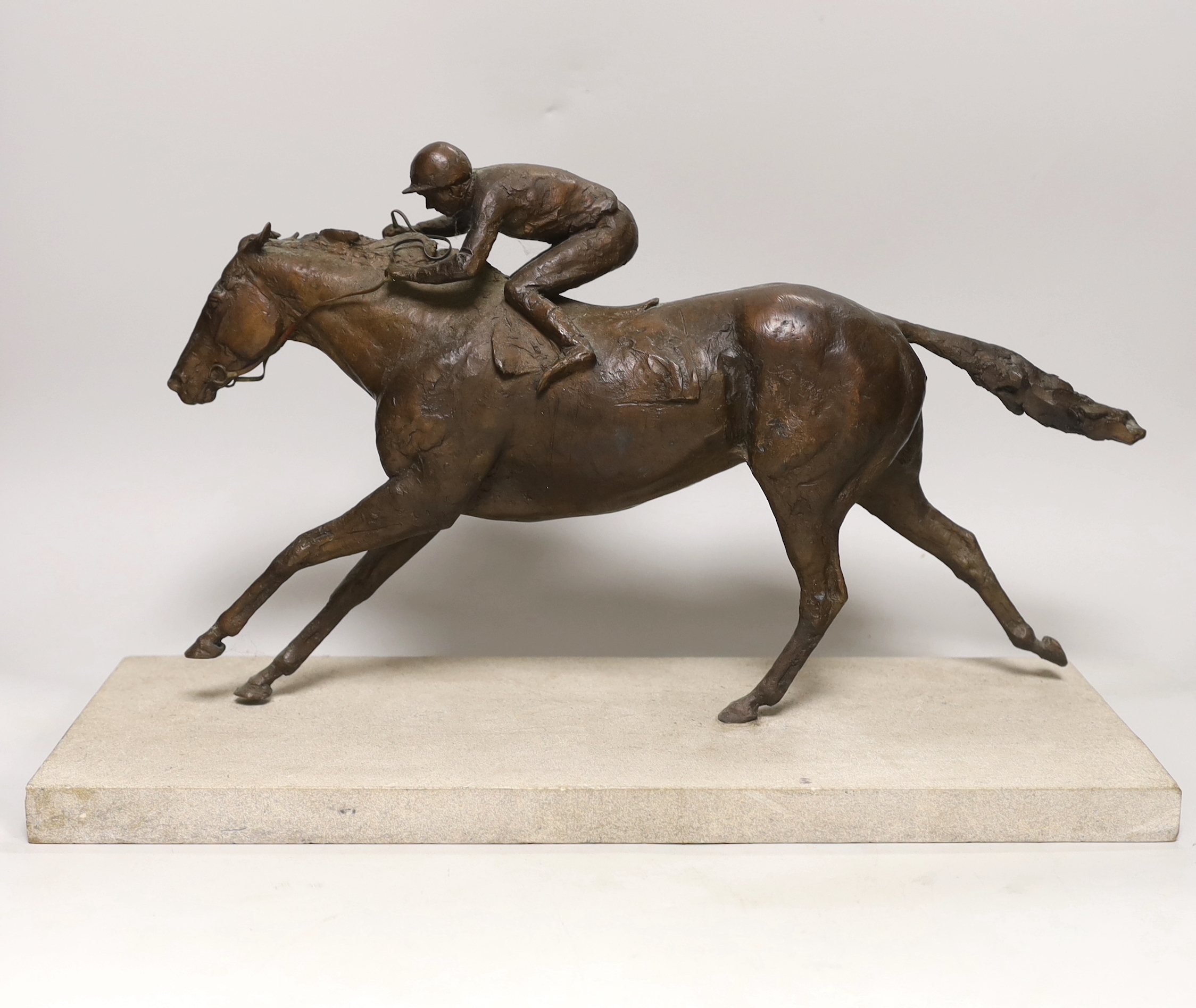 A patinated bronze of a racehorse with jockey, base 48cm long